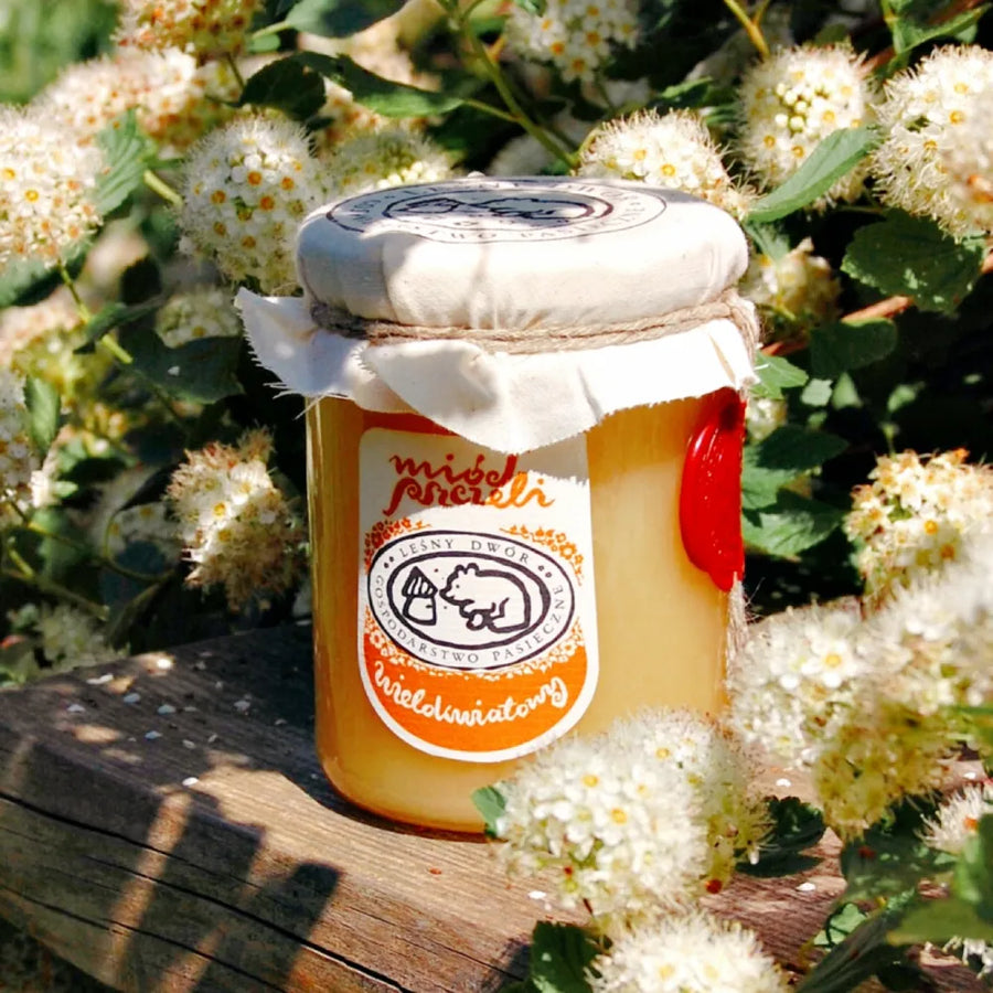 Słoik wiosennego miodu stojący wśród wiosennych kwiatów