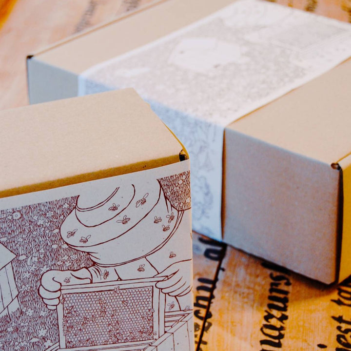 Ekologiczne pudełko kartonowe z papierową owijką, w które pakowany jest miód z owocami na prezent.